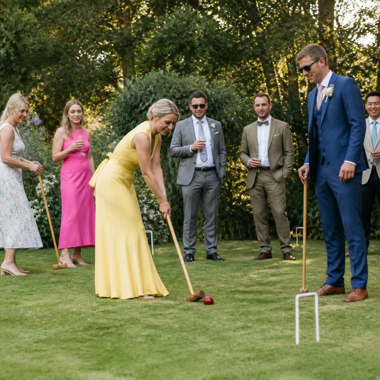 Wedding guests playing lawn croquet at a garden celebration